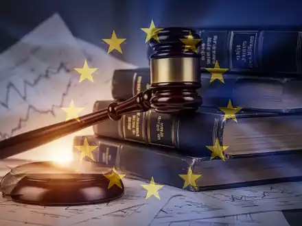 Ein stilisierter Hammer liegt auf einem Stapel von Gesetzbüchern mit einer subtilen Überlagerung eines EU-Flaggensymbols. - Foto: über boerse-global.de
