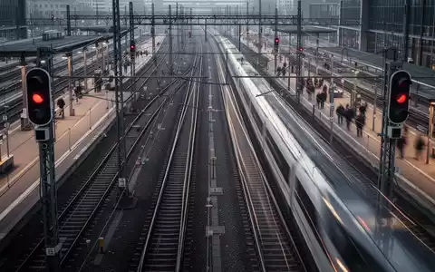Mehrere sich kreuzende Bahngleise an einem geschäftigen deutschen Bahnhof mit einem durchfahrenden Hochgeschwindigkeitszug. - Foto: über boerse-global.de