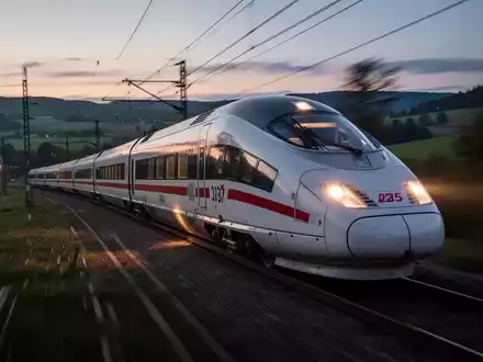 Ein moderner Hochgeschwindigkeitszug fährt bei Dämmerung durch eine verschwommene Landschaft, symbolisch für Pünktlichkeitsprobleme der Bahn. - Foto: über boerse-global.de
