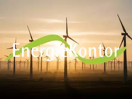 Windpark bei Sonnenaufgang mit riesigen Windturbinen, die sich gegen einen goldenen Himmel abzeichnen. - Foto: über boerse-global.de