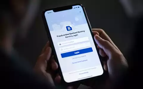 Nahaufnahme eines Smartphone-Bildschirms mit gefälschter Bank-Login-Seite, unscharfe Hände halten das Telefon im Hintergrund. - Foto: über boerse-global.de