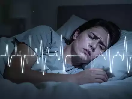 Eine schlaflose Person liegt nachts wach im Bett, mit einer subtilen Überlagerung eines Herzrhythmusmusters, das Insomnie und Herzgesundheit symbolisiert. - Foto: über boerse-global.de