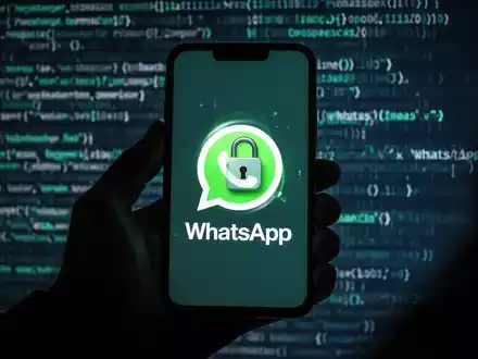Schattenhafte Hand hält Smartphone mit WhatsApp-Logo und digitalem Schloss, verschwommener Code im Hintergrund. - Foto: über boerse-global.de