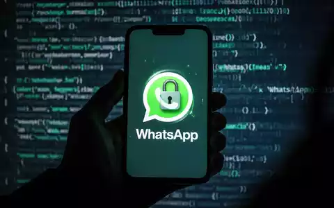 Schattenhafte Hand hält Smartphone mit WhatsApp-Logo und digitalem Schloss, verschwommener Code im Hintergrund. - Foto: über boerse-global.de