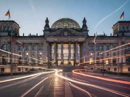 Eine stilisiert moderne Darstellung des Reichstagsgebäudes oder eines Parlaments mit Lichtspuren, die Aktivität und Reform andeuten. - Foto: über boerse-global.de
