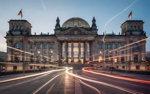 Eine stilisiert moderne Darstellung des Reichstagsgebäudes oder eines Parlaments mit Lichtspuren, die Aktivität und Reform andeuten. - Foto: über boerse-global.de