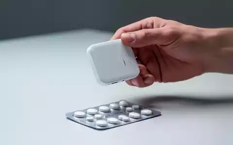 Eine Hand hält eine kleine, weiße Tablette über einer Blisterpackung, symbolisierend neue orale Medikamente zur Gewichtsabnahme. - Foto: über boerse-global.de