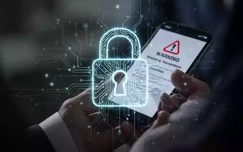 Ein stilisiertes digitales Vorhängeschloss-Symbol mit leuchtenden Schaltkreisen über einer Person, die ein Smartphone mit einer Warnmeldung hält. - Foto: über boerse-global.de