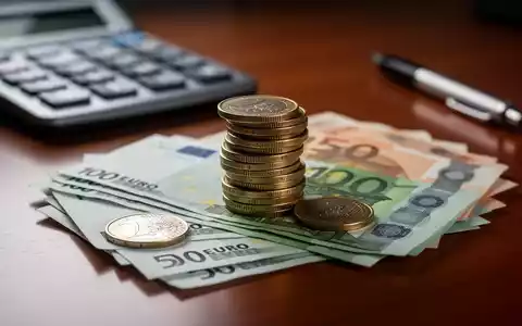 Nahaufnahme von Euro-Münzen und -Banknoten auf einem Schreibtisch mit einem Taschenrechner im Hintergrund, der Gesundheitskosten symbolisiert. - Foto: über boerse-global.de