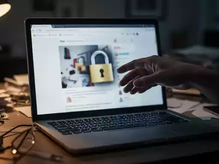 Eine Hand schwebt über einer Laptoptastatur, der Bildschirm zeigt eine verschwommene, betrügerische Online-Shop-Oberfläche. - Foto: über boerse-global.de
