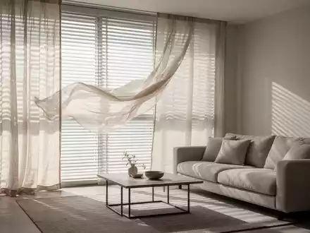 Ein kühles, ruhiges Wohnzimmer im Sommer mit heruntergelassenen Jalousien und weichen Leinenstoffen, die Schatten werfen. - Foto: über boerse-global.de