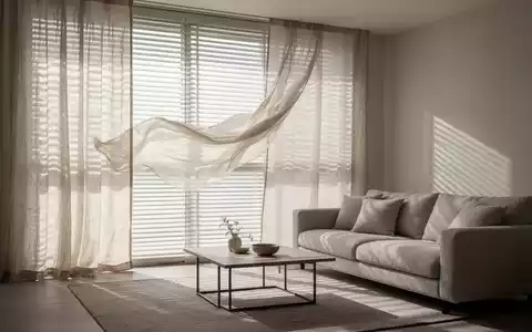 Ein kühles, ruhiges Wohnzimmer im Sommer mit heruntergelassenen Jalousien und weichen Leinenstoffen, die Schatten werfen. - Foto: über boerse-global.de