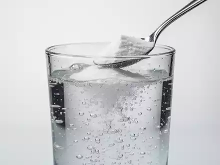 Ein Glas mit sprudelndem Wasser und einem Löffel Backpulver, das die fehlende wissenschaftliche Grundlage von Gesundheitstrends symbolisiert. - Foto: über boerse-global.de