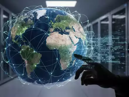 Stilisierte Weltkugel mit digitalen Verbindungen, Hand greift nach KI-Code, verschwommene Rechenzentren – Symbol für globale KI-Politik und Handel. - Foto: über boerse-global.de