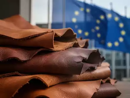Ein Stapel luxuriöser, texturierter Lederhäute in warmen Erdtönen, im Hintergrund verschwommen ein EU-Gebäude. - Foto: über boerse-global.de