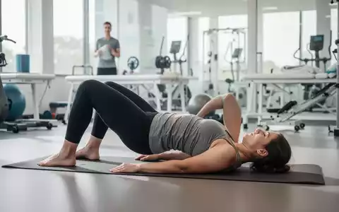 Eine Person führt eine Rückenübung auf einer Yogamatte in einem modernen, hellen Raum aus, fokussiert auf Bewegungstherapie. - Foto: über boerse-global.de
