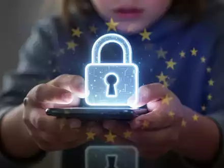 Leuchtendes digitales Vorhängeschloss-Symbol über unscharfen Händen eines Jugendlichen mit Smartphone, symbolisiert Online-Altersverifikation und Sicherheit. - Foto: über boerse-global.de