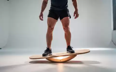 Eine Person in Sportkleidung steht auf einem Balance Board aus Holz, konzentriert sich auf das Gleichgewicht in einem hellen Studio. - Foto: über boerse-global.de