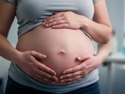 Hände einer Frau ruhen auf ihrem deutlich geschwollenen Bauch, der das Symptom des 'Endo-Belly' bei Endometriose darstellt. - Foto: über boerse-global.de
