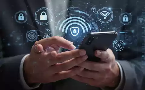 Hände halten ein Smartphone, im Hintergrund verschwommene digitale Sicherheitssymbole und Netzwerksignale, die SIM-Swap-Betrug darstellen. - Foto: über boerse-global.de