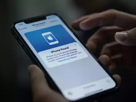 Nahaufnahme eines Smartphones, das eine betrĂŒgerische Phishing-Nachricht anzeigt, mit unscharfen HĂ€nden im Hintergrund. - Foto: ĂŒber boerse-global.de