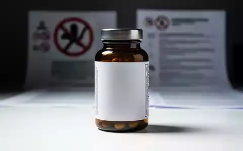 Eine generische Flasche Nahrungsergänzungsmittel auf einer weißen Oberfläche, unscharf im Hintergrund sind Symbole des Verbraucherschutzes. - Foto: über boerse-global.de