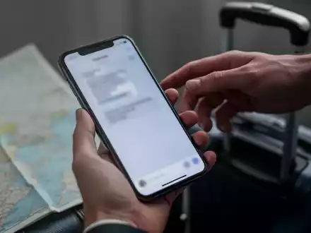 Eine Hand hält ein Smartphone, während eine andere Hand im Hintergrund danach greift, was Diebstahl und Betrug symbolisiert. - Foto: über boerse-global.de