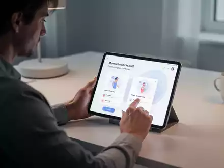 Eine Person sitzt an einem Schreibtisch und schaut auf ein Tablet, das eine App für psychische Gesundheit anzeigt. Die Umgebung ist modern und ruhig. - Foto: über boerse-global.de