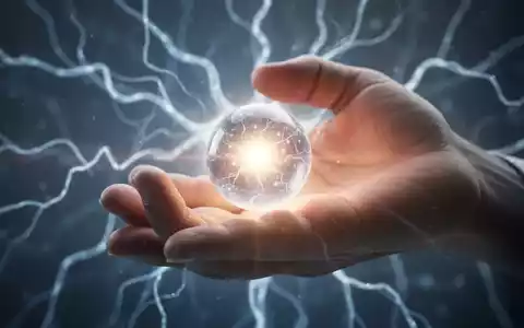 Eine Hand hält eine leuchtende Kugel, während im Hintergrund abstrakte Lichtmuster Elektrostimulation symbolisieren. - Foto: über boerse-global.de