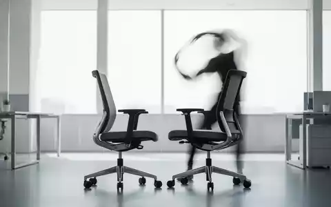 Eine Person macht Dehnübungen neben einem ergonomischen Bürostuhl in einem modernen, hellen Büro. - Foto: über boerse-global.de