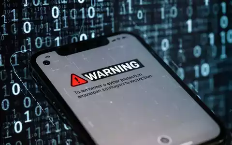 Nahaufnahme eines iPhone-Bildschirms mit einer 'Bösartige Nachricht erkannt'-Warnung, unscharfer digitaler Code im Hintergrund. - Foto: über boerse-global.de