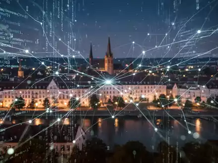 Digitale Datenströme und Netzwerkverbindungen überlagern eine verschwommene Nachtansicht von Bonn und symbolisieren Cybersicherheit und internationale Zusammenarbeit. - Foto: über boerse-global.de