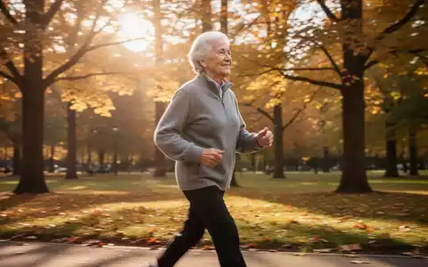 Eine ältere Person geht zügig durch einen sonnigen Park, umgeben von Herbstbäumen, und demonstriert Vitalität und Gesundheit. - Foto: über boerse-global.de