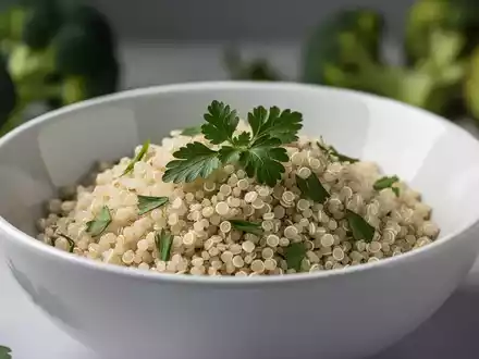 Nahaufnahme von gekochter Quinoa in einer weißen Schale, garniert mit frischen Kräutern, im Hintergrund verschwommenes Gemüse. - Foto: über boerse-global.de