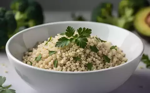 Nahaufnahme von gekochter Quinoa in einer weißen Schale, garniert mit frischen Kräutern, im Hintergrund verschwommenes Gemüse. - Foto: über boerse-global.de