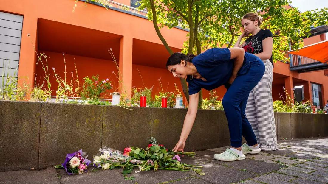 Menschen kommen vorbei und legen Blumen ab. - Bild: Andreas Arnold/dpa