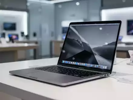 Ein schlankes, silbernes refurbished Laptop, vermutlich ein MacBook Pro, geöffnet auf einem sauberen Schreibtisch in einem modernen Umfeld. - Foto: über boerse-global.de