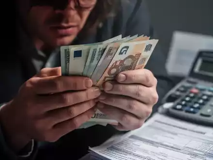 Nahaufnahme von Händen, die nervös Euro-Banknoten halten, im Hintergrund leicht verschwommen eine Rechnung. Symbolisiert finanzielle Sorgen. - Foto: über boerse-global.de