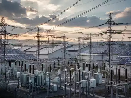Ein komplexes Netz aus Stromleitungen und Umspannwerken mit Solarpaneelen auf kommerziellen Dächern im Hintergrund. - Foto: über boerse-global.de