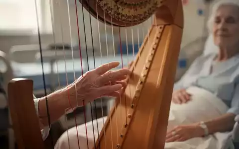 Eine Nahaufnahme der Hand eines Patienten, der sanft die Saiten einer Harfe in einer therapeutischen Umgebung berührt. - Foto: über boerse-global.de