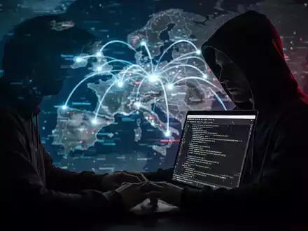 Eine Person mit Kapuzenpullover tippt an einem Laptop, auf dem Code zu sehen ist. Im Hintergrund eine stilisierte Europakarte mit leuchtenden Linien. - Foto: über boerse-global.de