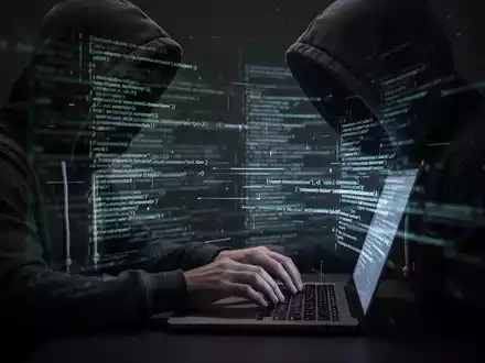 Eine Person im Kapuzenpullover tippt auf einem Laptop, digitale Linien und Code symbolisieren Cyberangriffe und Hacking. - Foto: über boerse-global.de
