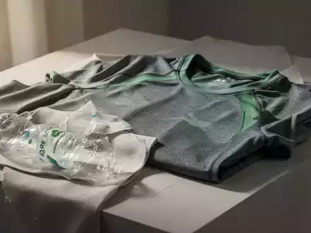 Nachhaltige Sportbekleidung aus recycelten Materialien, elegant auf einem minimalistischen Display arrangiert, mit weichem, natürlichem Licht. - Foto: über boerse-global.de