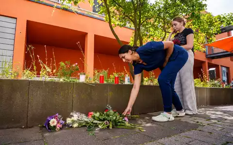 Menschen kommen vorbei und legen Blumen ab. - Foto: Andreas Arnold/dpa