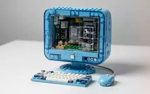 Detailliertes LEGO-Modell des Bondi Blue Apple iMac G3 mit durchsichtigen blauen Steinen, die innere Komponenten zeigen, neben einer Miniatur-LEGO-Tastatur und -Maus. - Foto: über boerse-global.de