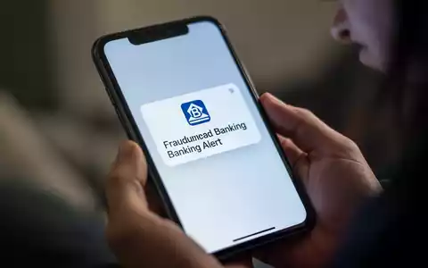 Nahaufnahme eines Smartphone-Bildschirms mit betrügerischer Bankwarnung, in den Händen einer Person. - Foto: über boerse-global.de