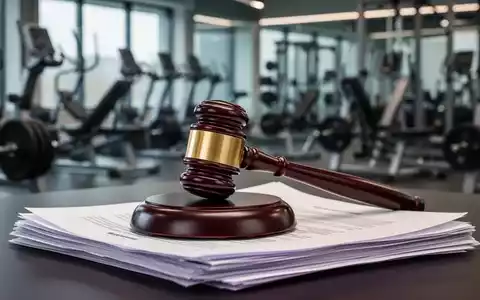Ein stilisierter Hammer ruht auf einem Stapel juristischer Dokumente vor einem unscharfen Hintergrund mit modernen Fitnessgeräten. - Foto: über boerse-global.de
