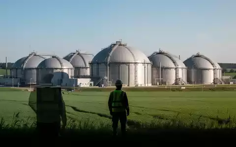 Eine Biogasanlage mit großen, kuppelförmigen Fermentern und einem Techniker im Vordergrund, der die Anlage inspiziert. - Foto: über boerse-global.de