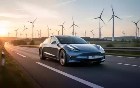 Ein modernes Elektroauto fährt auf einer deutschen Autobahn bei Sonnenaufgang, mit Windturbinen im Hintergrund. - Foto: über boerse-global.de