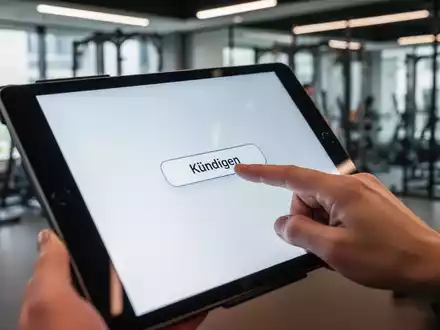 Ein Finger drückt auf einem Tablet einen digitalen Kündigen-Button, im Hintergrund ein unscharfes Fitnessstudio. Fokus auf Transparenz und Nutzerführung. - Foto: über boerse-global.de